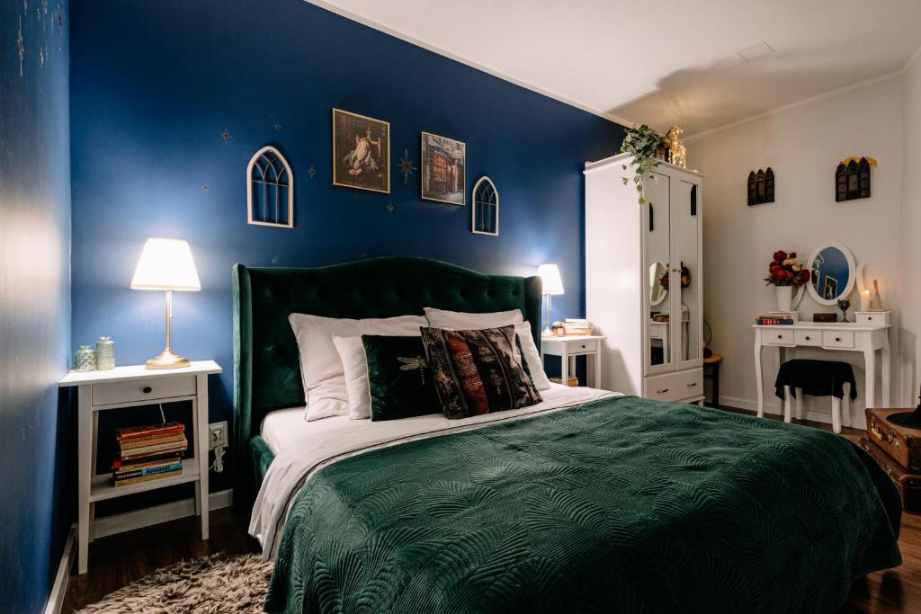 a bedroom with a green bed and blue walls at Magiczny Salonik Harrego - Magical Old Town Apartment in Toruń