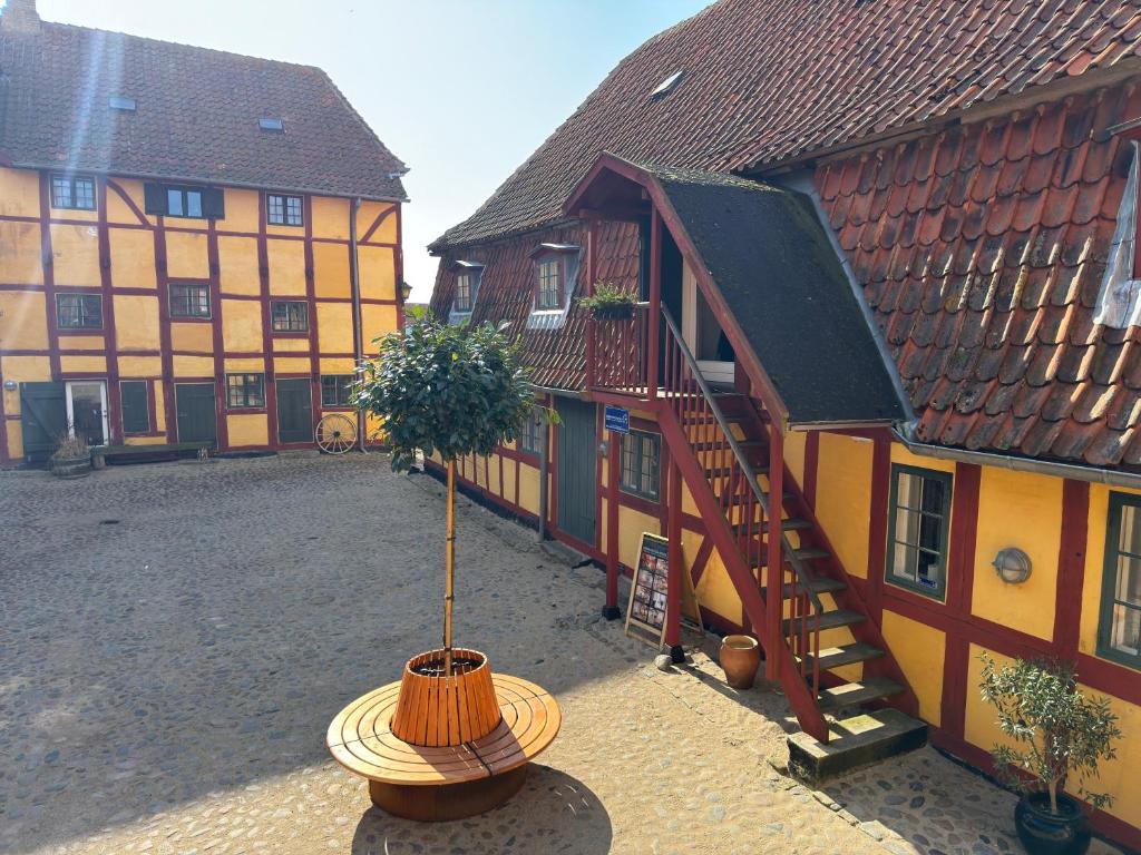 a building with a potted tree in a courtyard at Købmandsgaarden Kerteminde in Kerteminde