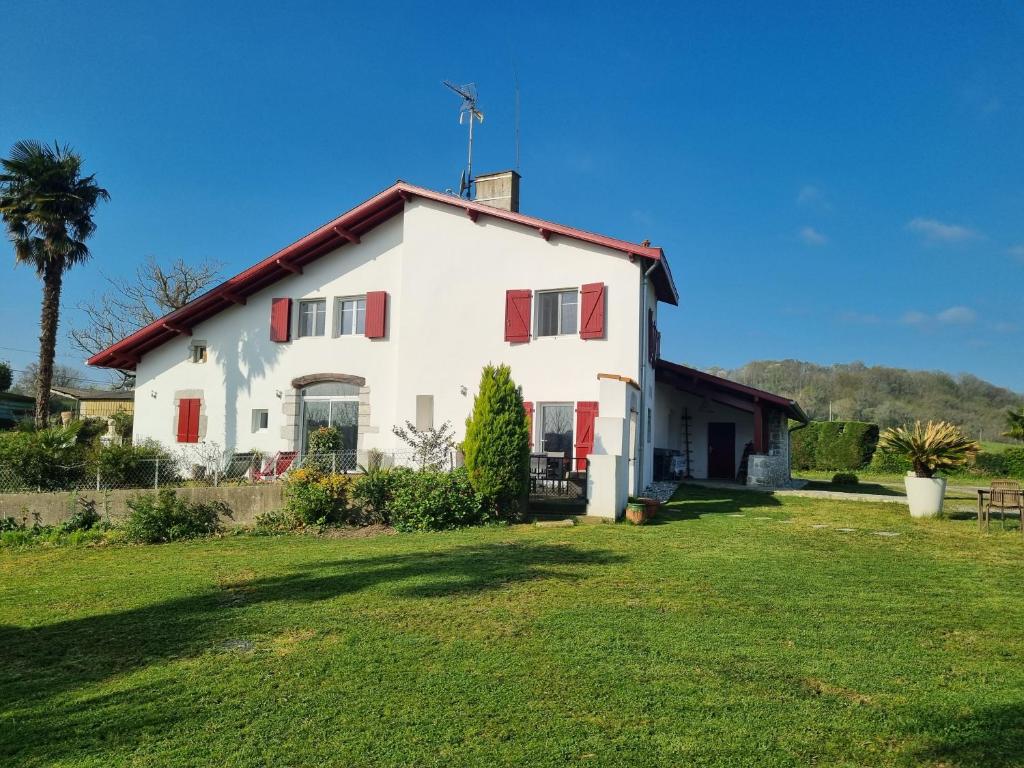 a white house with red doors and a yard at Maison Arios in Came