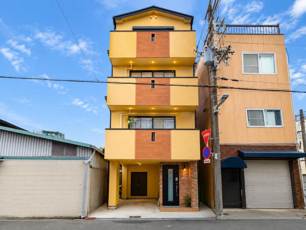 a tall yellow building on a city street at K2Guesthouse Konohana in Osaka