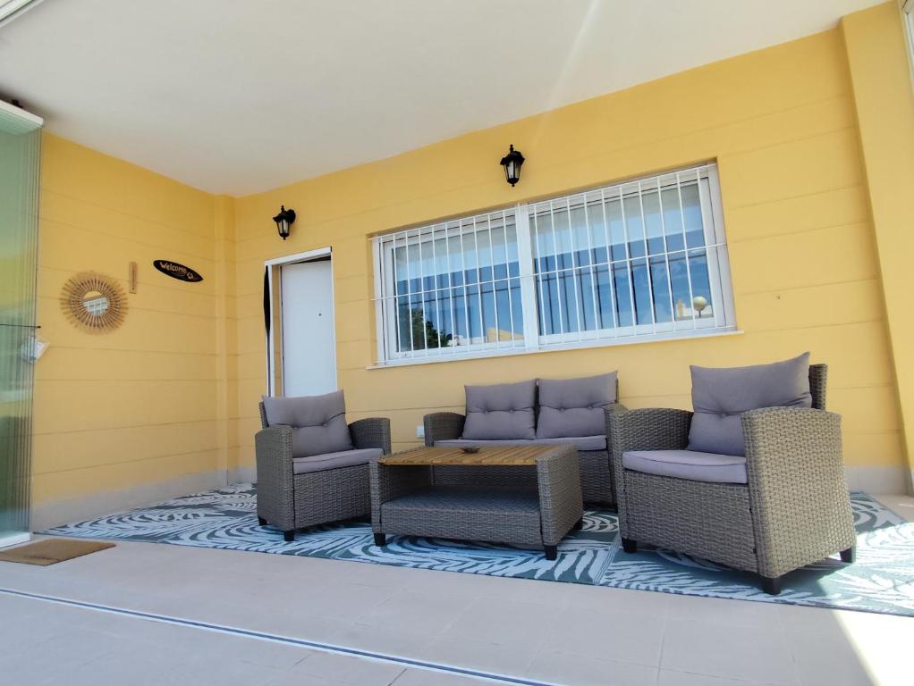 a patio with chairs and a table and windows at Chalet adosado acogedor Busot in Alicante