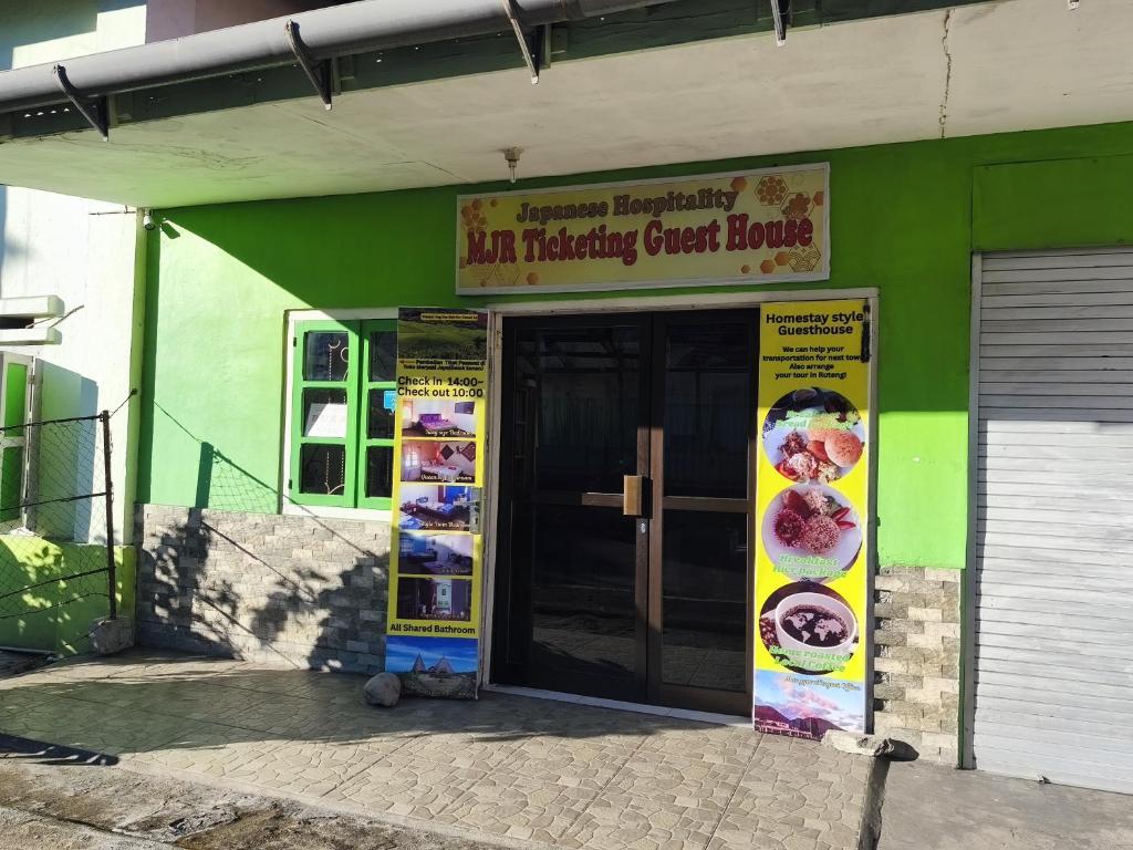 a green building with a sign for an interesting guest house at MJR Ticketing Guest House in Ruteng