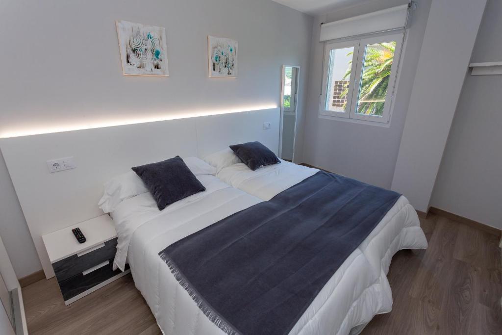 a bedroom with a large bed with white sheets and a window at Apartamentos Raices in Cee