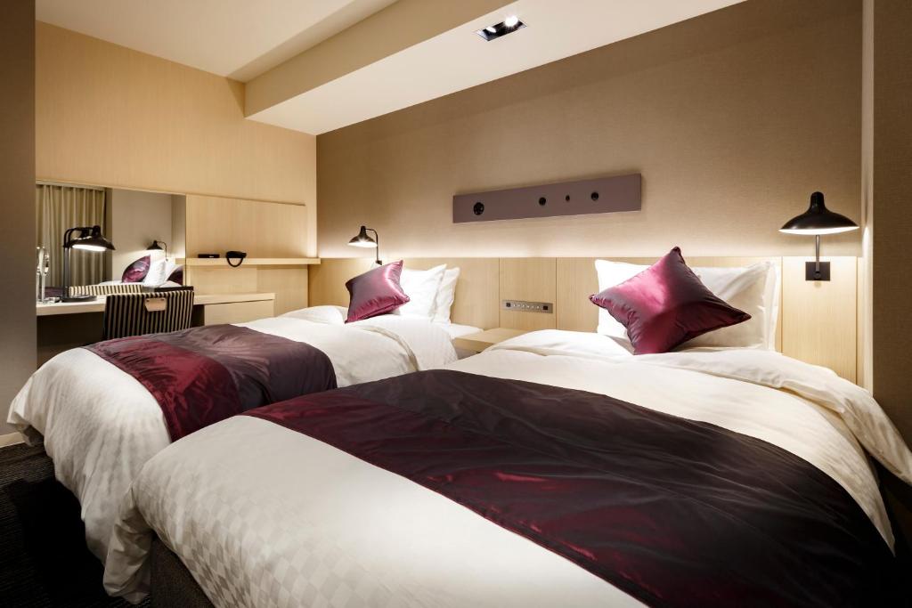 a hotel room with two beds with red and white sheets at Hotel Vista Sendai in Sendai