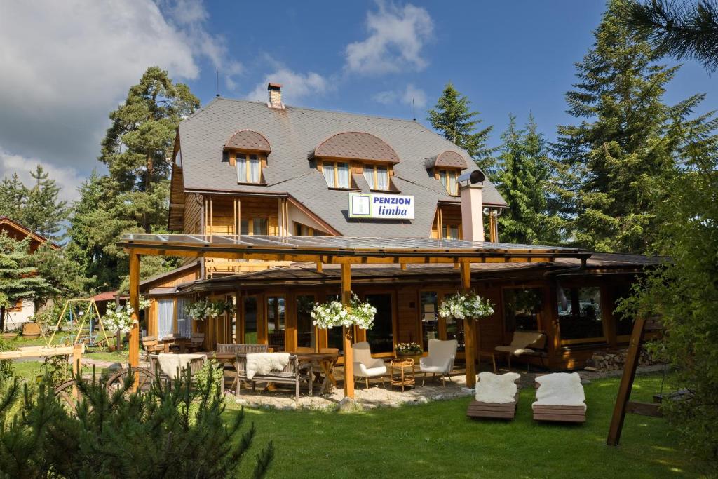 a large wooden house with chairs and tables in a yard at Penzion Limba in Belá