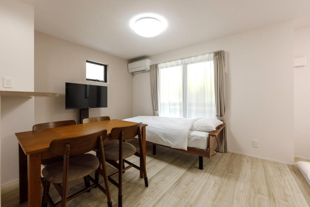 a bedroom with a bed and a table and chairs at Anecis名楽町 in Nagoya