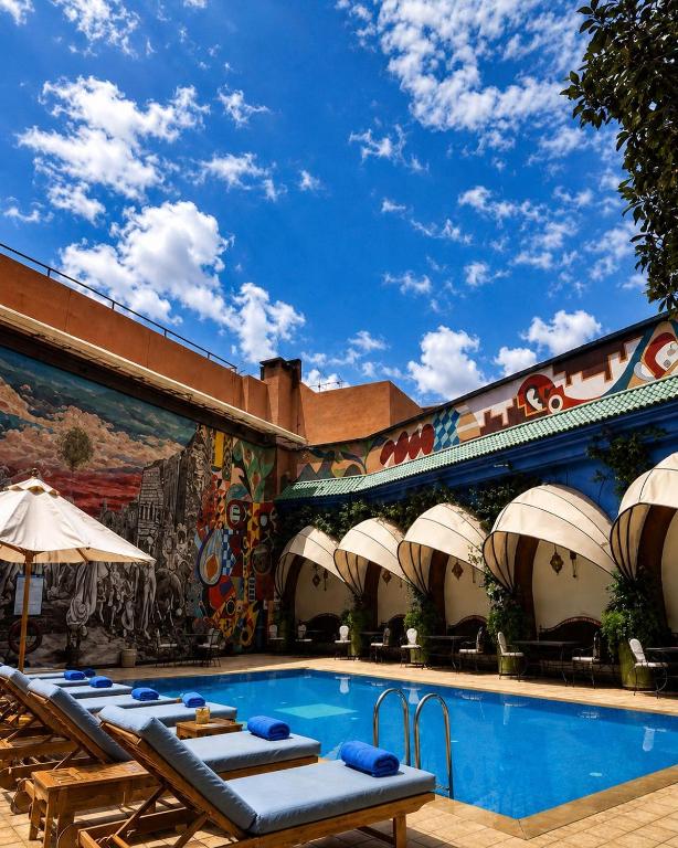 a pool with lounge chairs next to a building at Blue Sea Le Printemps in Marrakesh