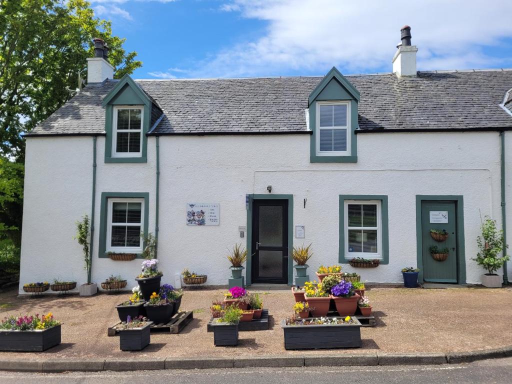 a white house with potted plants in front of it at The House at Glenbarr Stores in Glenbarr
