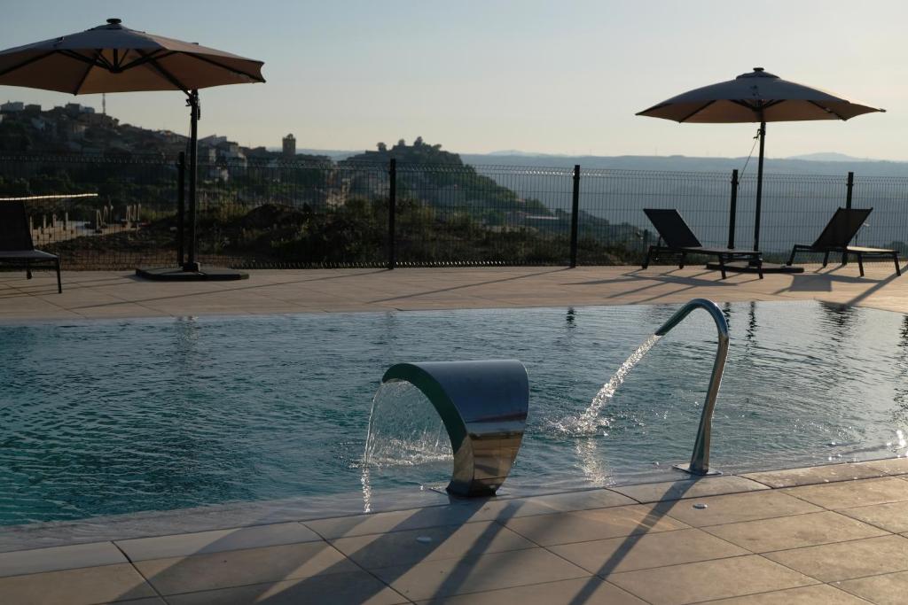 a water fountain in a pool with two umbrellas at Apartamentos Doña Urraca in Fermoselle