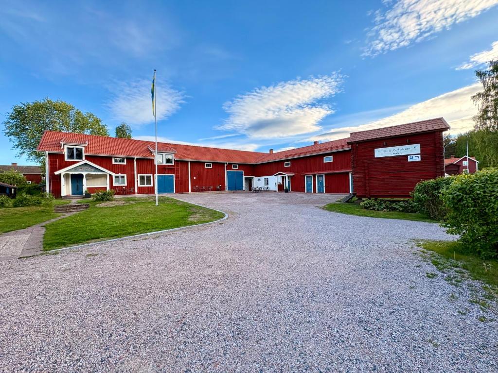 a red barn with a driveway in front of it at B&B Parkgården Leksand in Leksand