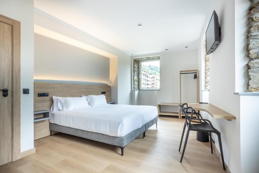 a hotel room with a bed and a desk at Hotel Truita in Cangas del Narcea