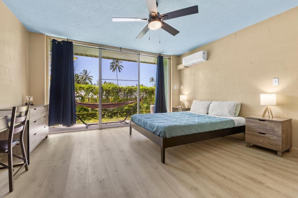 a bedroom with a bed and a large window at Garden Balcony • Walk to Beach + Kitchen in Hilo