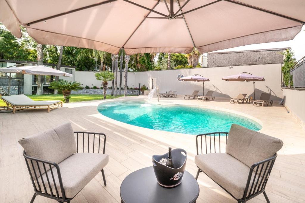 a swimming pool with two chairs and an umbrella at HOLIDAYS ALBA in Catania