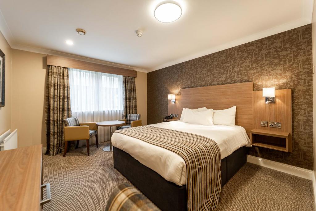 a hotel room with a bed and a table at Corr's Corner Hotel in Newtownabbey