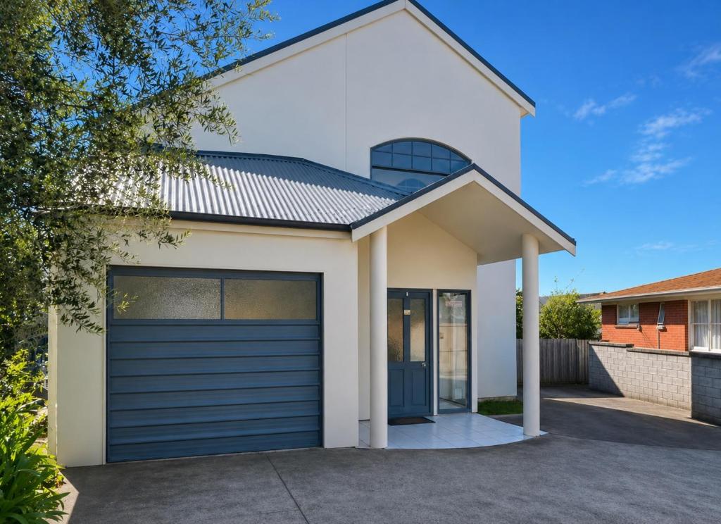 a white house with a blue garage door at Tauranga Harbour View in Tauranga