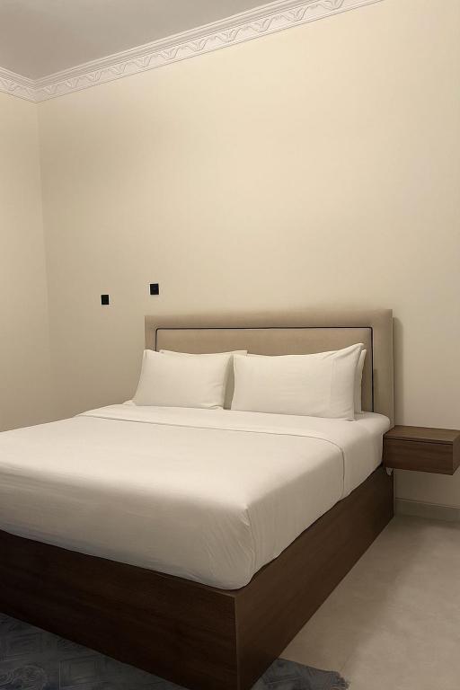 a large bed with white sheets and pillows at الارجان للشقق المفروشة in Al Nairyah