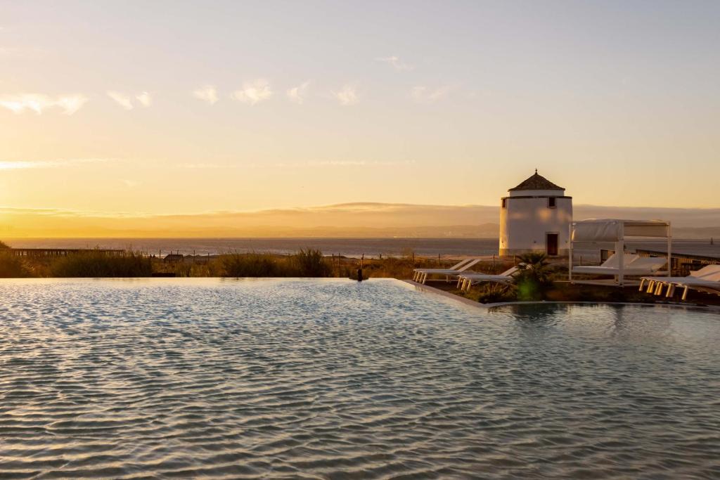 a swimming pool with a lighthouse in the distance at Praia do Sal Resort & SPA in Alcochete