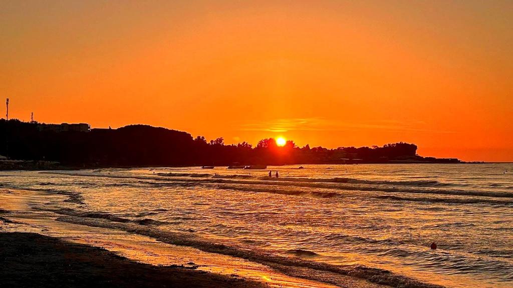 a sunset on a beach with the sun setting at Dolphin Apt & Studios -Near the Beach in Roda