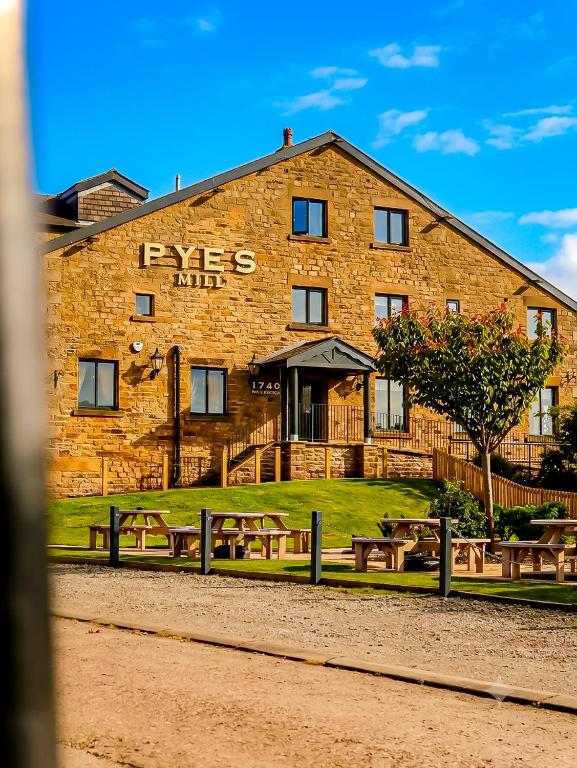 a large brick building with benches in front of it at Pyes Mill Hotel Lancaster in Conder Green