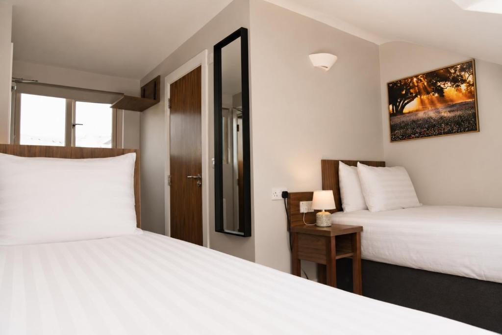 a bedroom with two beds and a table with a lamp at Coach House Accommodation - Room 6 in Carrick on Shannon