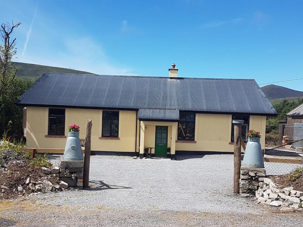 a yellow house with a black roof and a gate at The Old Creamery Ventry in Ventry