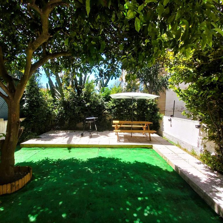 a small green pool with a table and an umbrella at Garden Apartment with BBQ & Orange Tree - Near Lisbon & Sintra in Queluz