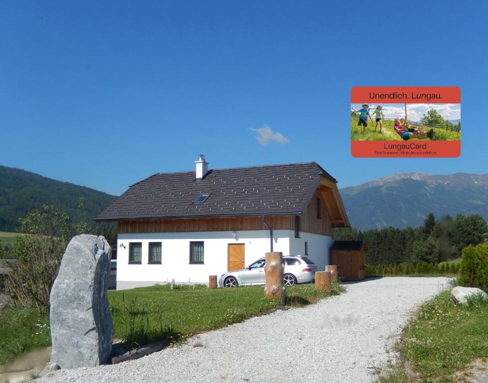 a white house with a car parked in front of it at AlpenChalet Mitterberg in Mariapfarr