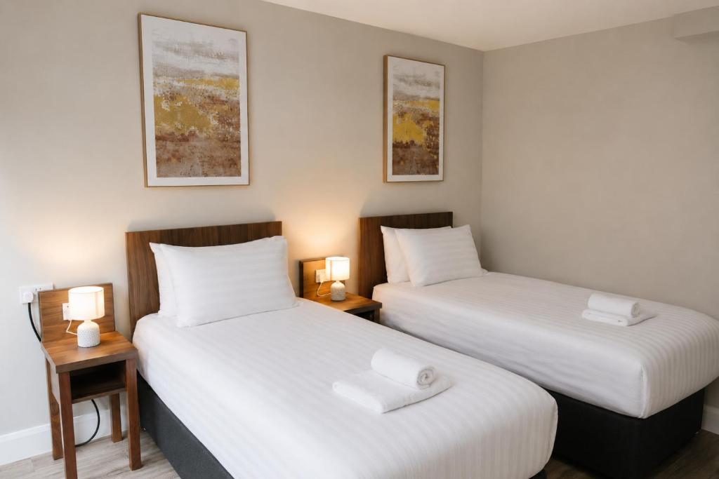 two beds in a small room with two lamps at Coach House Accommodation - Room 8 in Carrick on Shannon