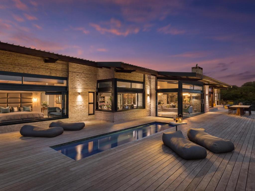 a house with a swimming pool on a wooden deck at Heaven's Door Main House in Stilbaai