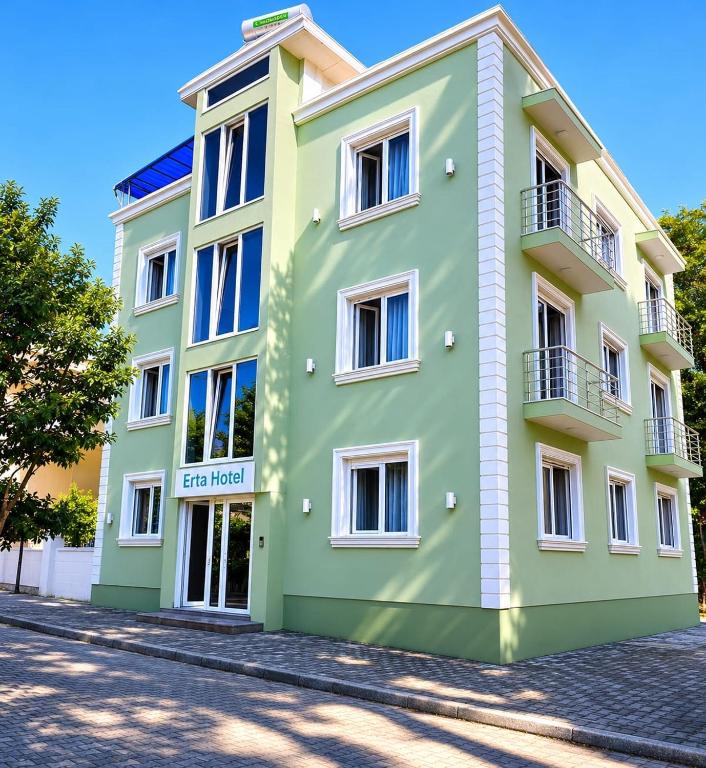 a green and white building on a street at Hotel Erta in Golem