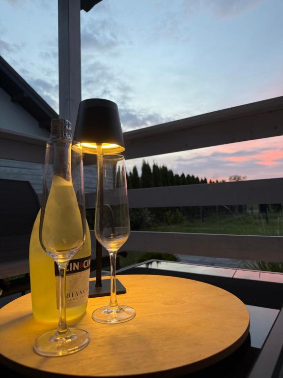 two glasses of wine on a table with a lamp at Domki u Izabeli niedaleko Darłowa in Rusko