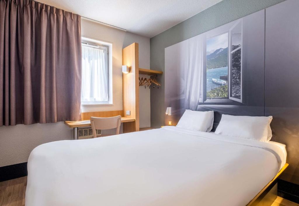 a large white bed in a room with a window at B&B HOTEL Annecy Argonay in Argonay
