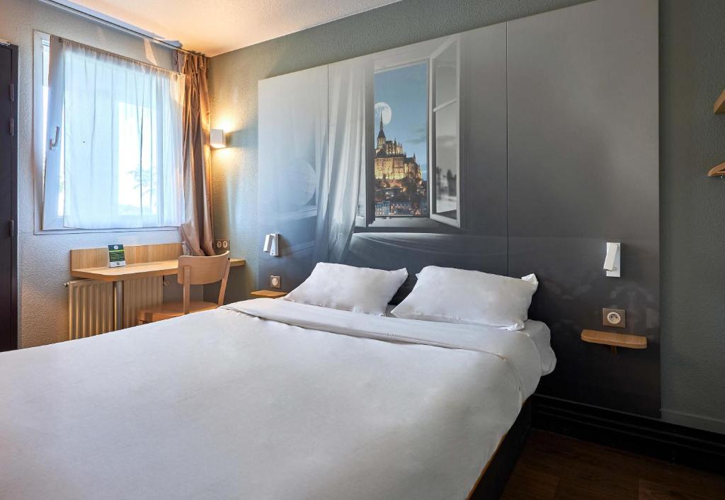 a bedroom with a large white bed and a desk at B&B HOTEL AVRANCHES Baie du Mont St-Michel in Le Val-Saint-Père
