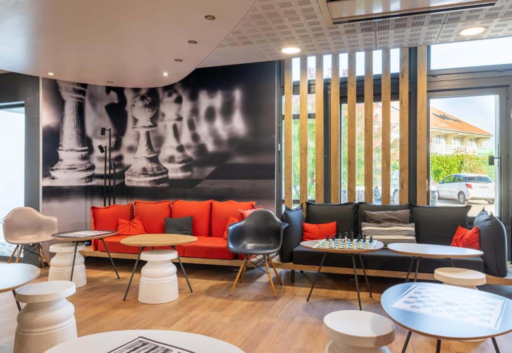 a waiting room with a red couch and tables at B&B HOTEL Lyon Eurexpo Bron in Bron