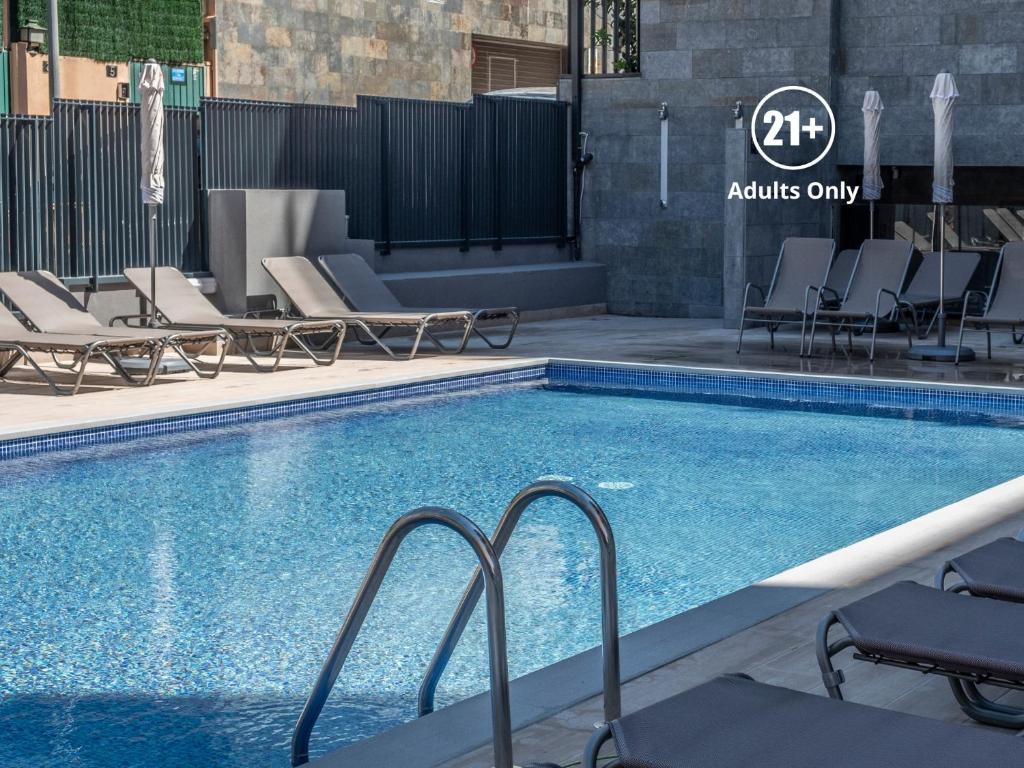 a swimming pool with lounge chairs next to a building at Rosamar Es Blau 4*s - Adults Only in Lloret de Mar