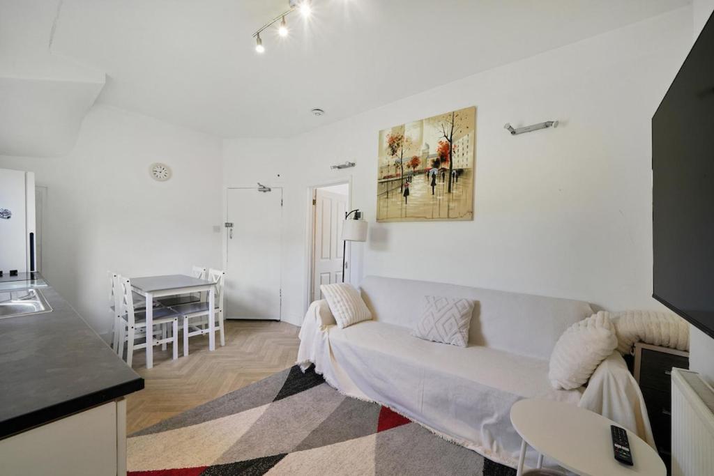 a white living room with a couch and a painting on the wall at Garden Flat In Watford in Watford West Station