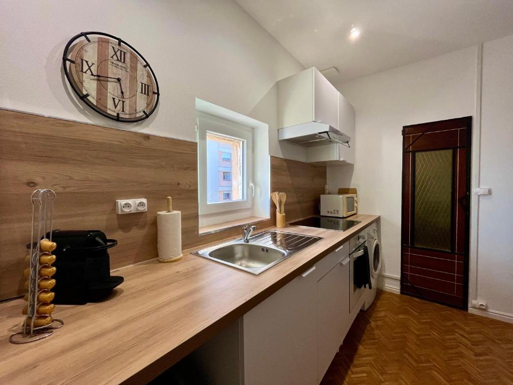 a kitchen with a sink and a clock on the wall at L'essentiel Gare d'Oullins - 3 chambres - 15 min de Lyon in Oullins