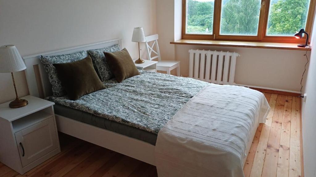 a bed in a bedroom with two tables and two windows at Light street in Ķekava