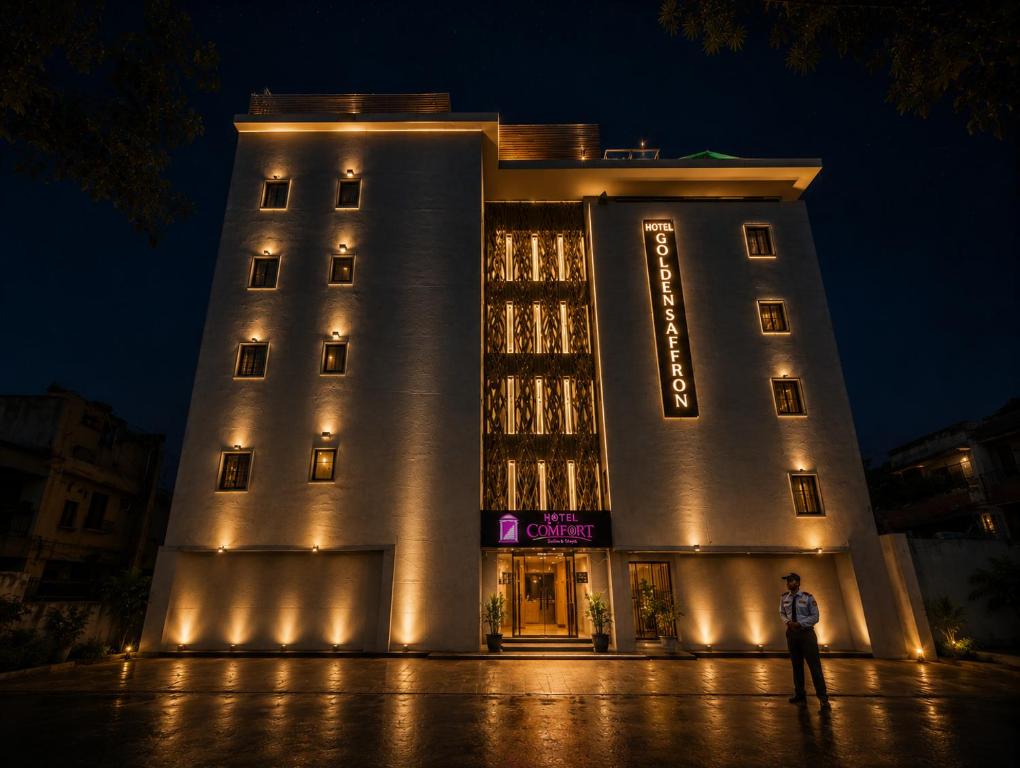 a man standing in front of a building at night at Qotel Comfort Golden Saffron - Hotel in Punjabi Bagh Near Metro in New Delhi