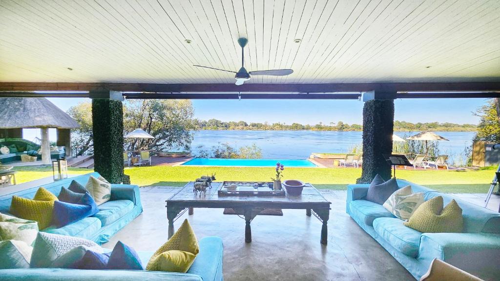 a living room with blue couches and a table at Mukwa River Lodge in Livingstone