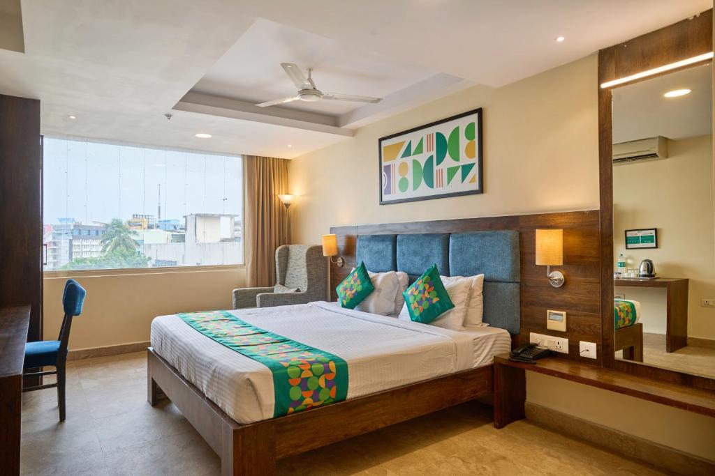 a bedroom with a bed and a desk and a window at Treebo Premium PL Grand, Visakhapatnam in Visakhapatnam
