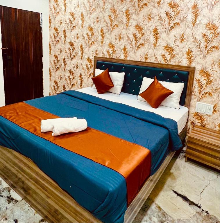 a bed with orange and blue sheets and pillows at Yash Residency Lodging And Boarding in Ulhāsnagar