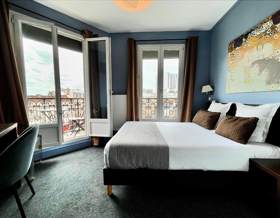 a bedroom with a large bed with blue walls and windows at Hôtel Odessa Montparnasse in Paris