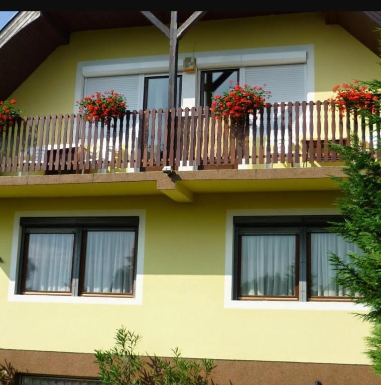 a building with a balcony with flowers on it at Mimóza Vendégház - Csaba Vendégház in Balatonszemes