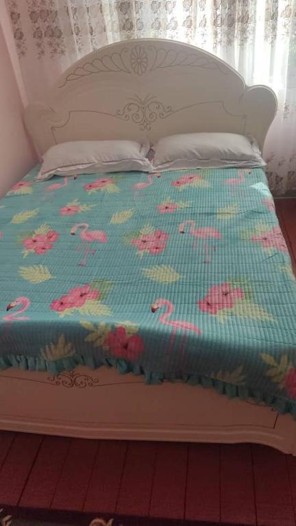 a white bed with a blue blanket with pink flowers at Ночлег с завтраком in Dzhangyaryk