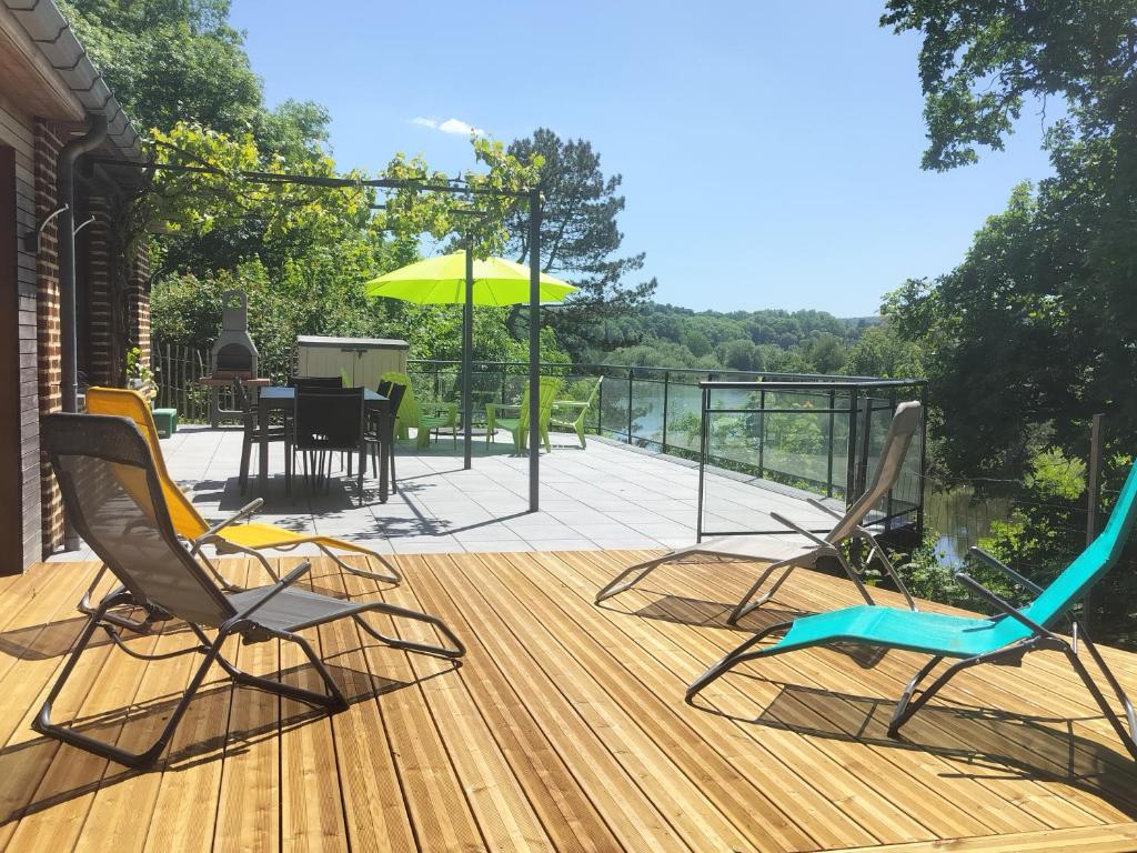two chairs and an umbrella on a wooden deck at L'Éphém'Heer in Hastière-par-delà