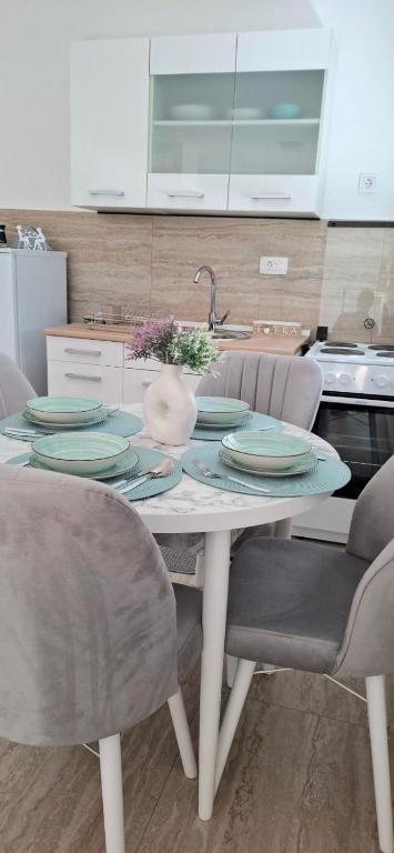 a dining room table with chairs and plates on it at Cherry Garden Apartment in Podgorica