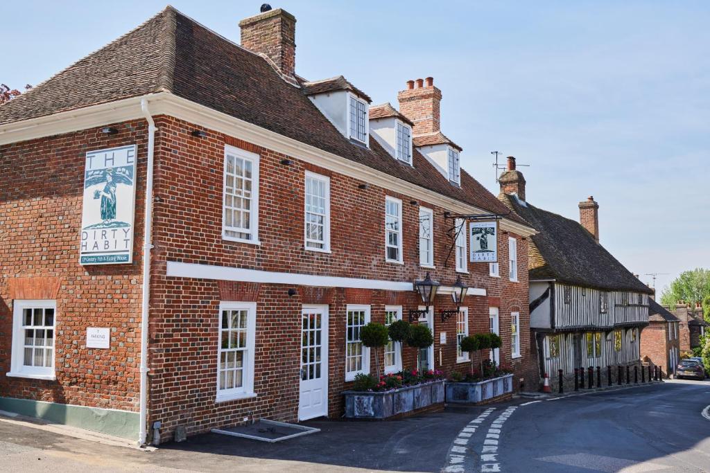 a red brick building with white windows on a street at The Dirty Habit in Hollingbourne