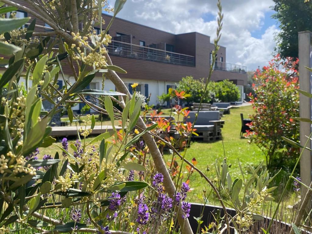 a garden with flowers in front of a building at Hôtel des Argousiers in Ambleteuse