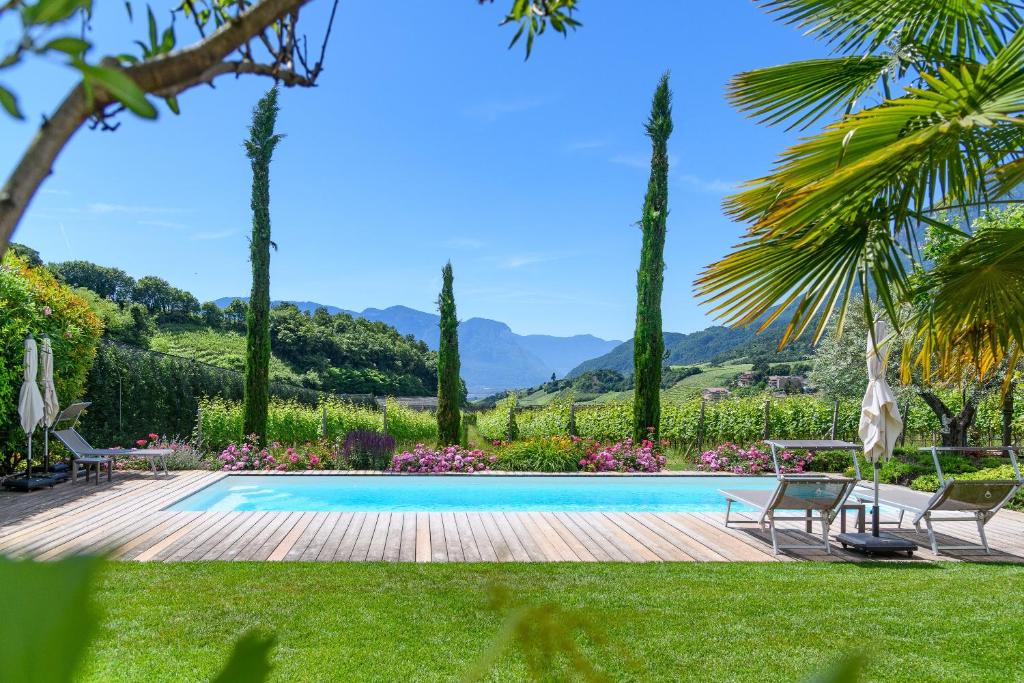 a pool in a garden with chairs and trees at Kardonighof Kaltern in Caldaro